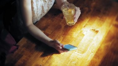 bir kadın bir restoranda bir kokteyl içer ve telefon kullanır