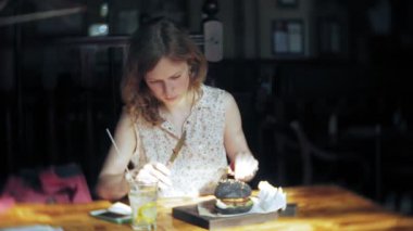 Genç kadın yemek lokanta, siyah hamburger