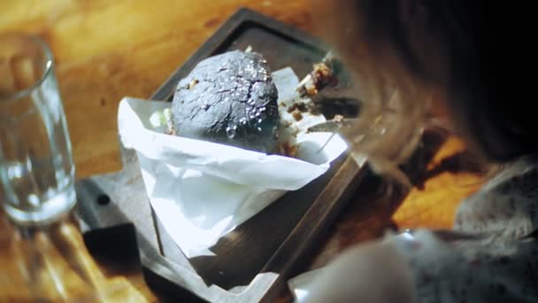若い女性食べるファーストフード、黒ハンバーグ — ストック動画