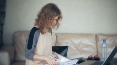 Divan tablet ile masada oturan ve kağıt arıyor genç güzel iş kadını