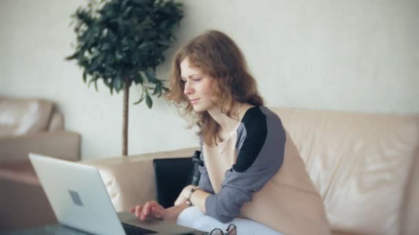 Junge schöne Geschäftsfrau sitzt auf Sofa am Tisch mit Tablet — Stockvideo