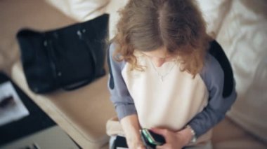 Divan tablet ile masada oturan ve smartphone kullanarak genç güzel iş kadını