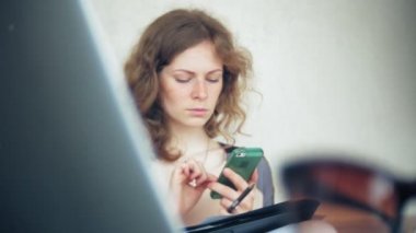 Divan tablet ile masada oturan ve smartphone kullanarak genç güzel iş kadını