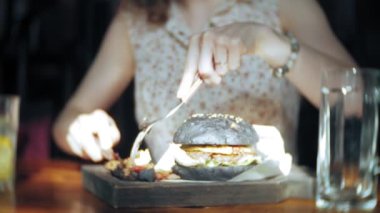 Genç kadın yemek lokanta, siyah hamburger
