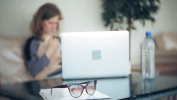 Jeune belle femme d'affaires assise sur un canapé à table avec tablette et utilisant un smartphone — Video