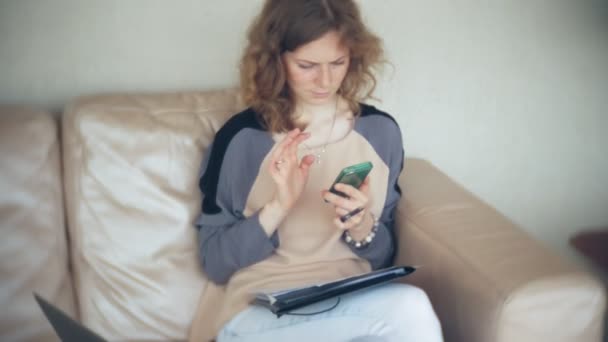 Joven mujer de negocios hermosa sentado en el sofá en la mesa con la tableta y el uso de teléfono inteligente — Vídeos de Stock