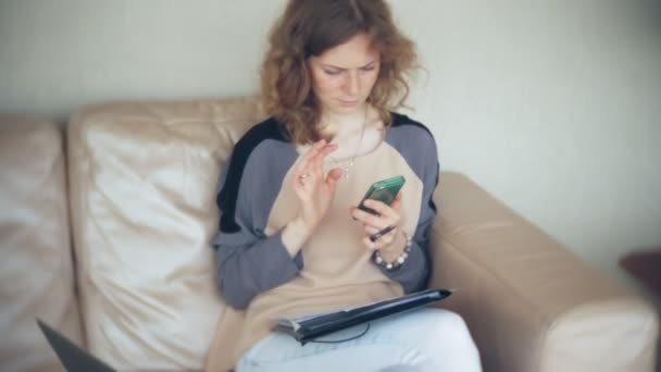 Jonge mooie zakenvrouw zittend op de Bank aan tafel met tablet en smartphone gebruiken — Stockvideo