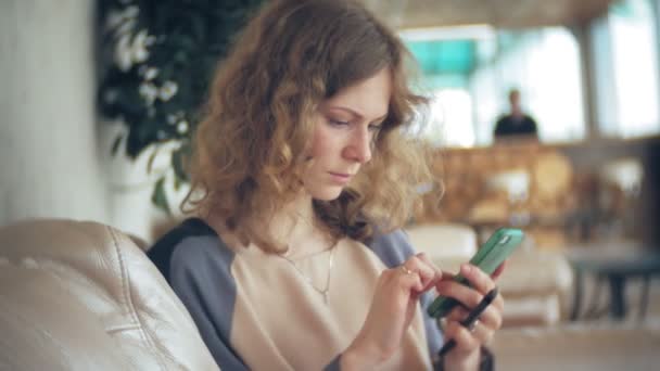 Divan tablet ile masada oturan ve smartphone kullanarak genç güzel iş kadını — Stok video