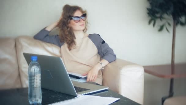 Joven mujer de negocios hermosa sentado en el sofá en la mesa con la tableta y el uso de teléfono inteligente — Vídeos de Stock