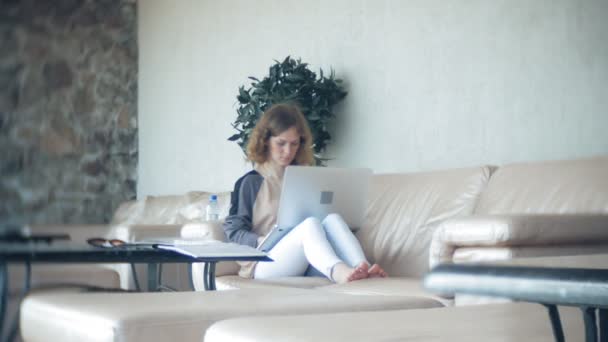 Jeune belle femme d'affaires assise sur un canapé à table avec tablette 