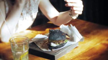 Genç kadın yemek lokanta, siyah hamburger