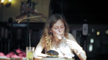 Genç kadın yemek lokanta, siyah hamburger