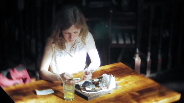 Young woman eating fast food, black hamburger — Stock Video