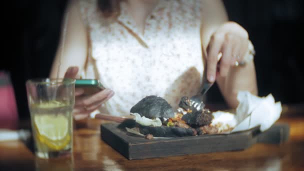 Jonge vrouw eten fastfood, zwarte hamburger — Stockvideo