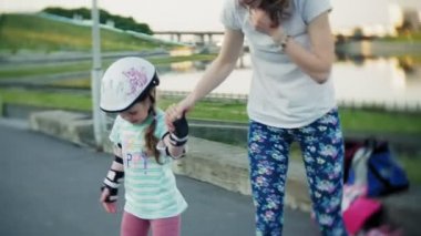 Annesi kızının paten parkta kaymayı yardımcı olur.