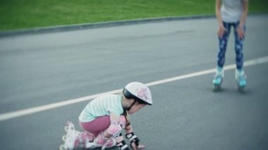 Annesi kızının paten parkta kaymayı yardımcı olur.