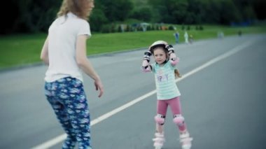 Annesi kızının paten parkta kaymayı yardımcı olur.