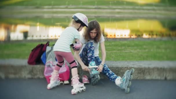 Mãe ajuda sua filha a patinar em um parque de patinação — Vídeo de Stock