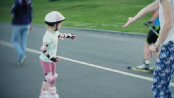 Мама помогает дочери кататься на роликах в парке — стоковое видео