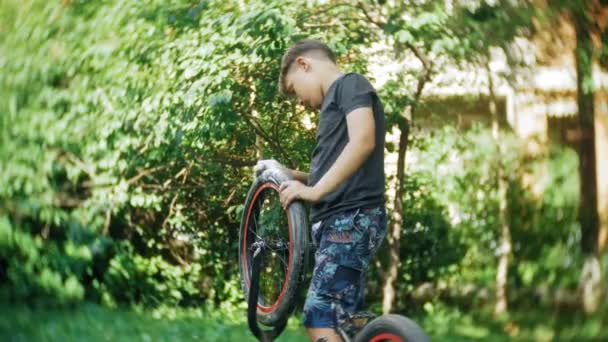 Мальчик моет свой велосипед BMX водой и пеной — стоковое видео