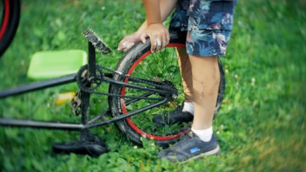 Der Junge wäscht sein Fahrrad mit Wasser und Schaum — Stockvideo