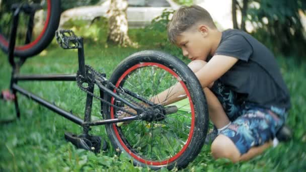 The boy washes his BMX bicycle with water and foam — Stock Video