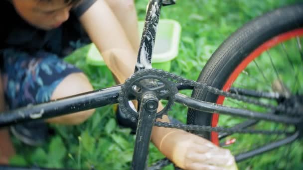 Мальчик моет свой велосипед BMX водой и пеной — стоковое видео