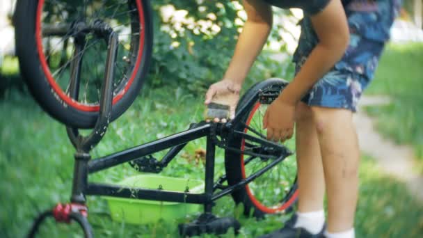 男孩用水和泡沫洗他的小轮车自行车4K — 图库视频影像