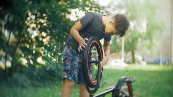 男孩用水和泡沫洗他的小轮车自行车。 — 图库视频影像