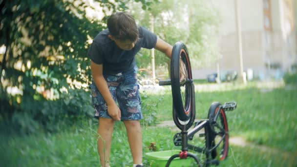El niño lava su bicicleta BMX con agua y espuma — Vídeos de Stock