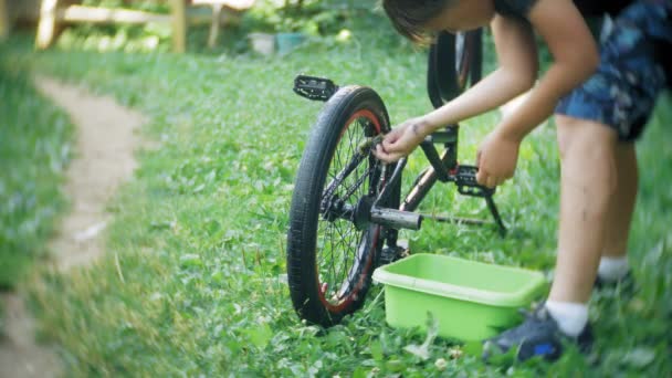 The boy washes his BMX bicycle with water and foam — Stock Video