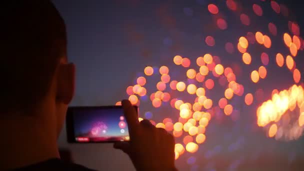 スマート フォンを持つ人の見物人。クローズ アップ手電話で花火を写真します。 — ストック動画