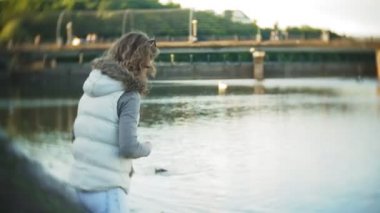 Genç bir kadın bir gölde besleme kuğu ve kışın kuş besleme ördekler