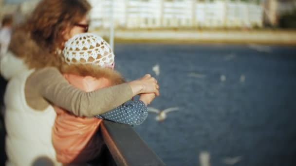 若い女性と彼女の娘を食べる鳥に与えるカモメ川 — ストック動画