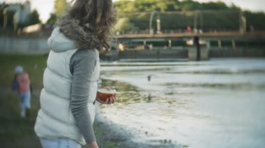 Genç bir kadın bir gölde besleme kuğu ve kışın kuş besleme ördekler