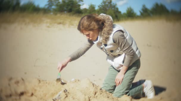 La donna è impegnata nello scavo di ossa nella sabbia, scheletro e strumenti archeologici . — Video Stock