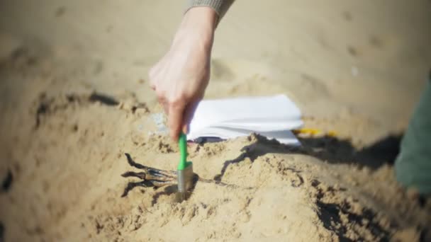 De vrouw is betrokken bij graafwerkzaamheden botten in het zand, het skelet en de archeologische tools. — Stockvideo