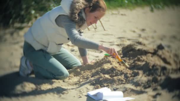 Die Frau ist damit beschäftigt, Knochen im Sand, Skelette und archäologische Werkzeuge auszugraben. — Stockvideo