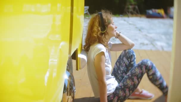 Mujer joven al aire libre por vagón amarillo coche escuchar música en los auriculares con el teléfono inteligente - relajarse, disfrutar, concepto de la tecnología y viajar — Vídeos de Stock