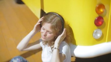 Genç kadın açık havada tarafından sarı vagon araba müzik dinleme smartphone kullanarak - rahatlatıcı, zevk, kulaklık kavramı teknoloji ve seyahat