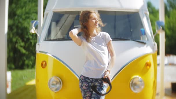 젊은 여성 야외 노란색 vagon 자동차 듣는 음악으로 헤드폰 스마트폰을 사용 하 여-휴식, 기술 및 여행의 개념 — 비디오