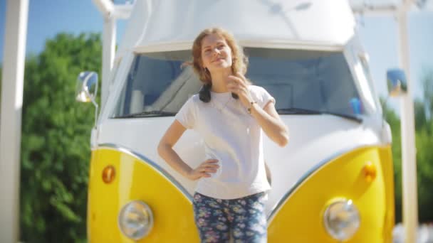 젊은 여성 야외 노란색 vagon 자동차 듣는 음악으로 헤드폰 스마트폰을 사용 하 여-휴식, 기술 및 여행의 개념 — 비디오