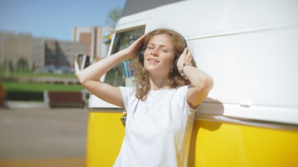 Jeune femme en plein air par voiture de vagon jaune écouter de la musique dans les écouteurs à l'aide d'un smartphone relaxant, profiter, concept de technologie et Voyage — Video