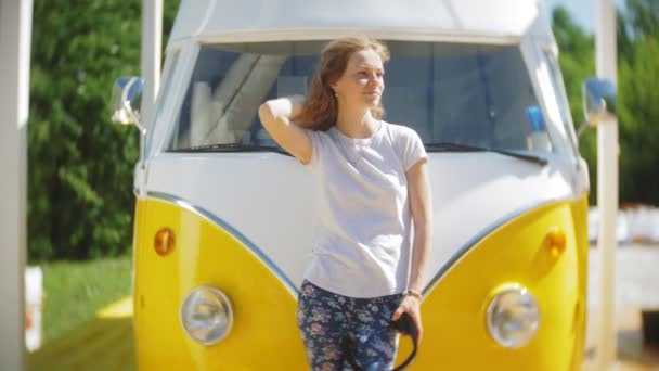 Ung kvinna Utomhus vid gula vagon bil lyssnar musik i hörlurar använder smartphone - avslappnande, njuter, begreppet teknik och resor — Stockvideo