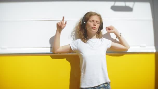 Mujer joven al aire libre por vagón amarillo coche escuchar música en los auriculares con el teléfono inteligente - relajarse, disfrutar, concepto de la tecnología y viajar — Vídeo de stock