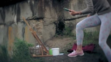 Genç kadın şövale boya ve fırça eski vintage köprünün üzerinde çizer