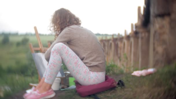 Jeune femme dessine sur le chevalet peintures et brosse vieux pont vintage — Video