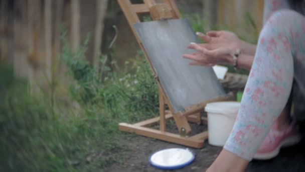 Jeune femme dessine sur le chevalet peintures et brosse vieux pont vintage — Video