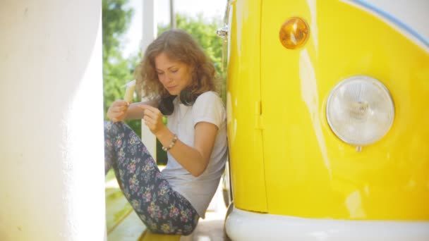 Jovem ao ar livre por vagão amarelo carro ouvindo música em fones de ouvido usando smartphone - relaxante, desfrutando, conceito de tecnologia e viagens — Vídeo de Stock