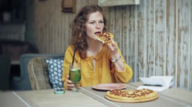 Genç bir kadın bir kafe barda bir pasta yiyor ve bir telefon kullanır